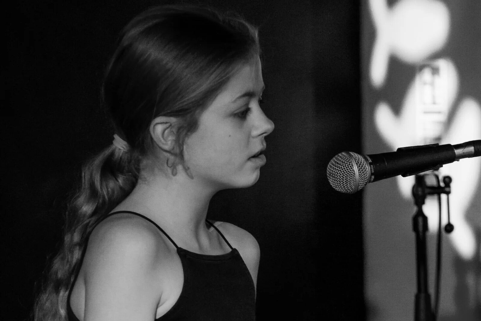 teenager in a black top singing into a microphone to make money