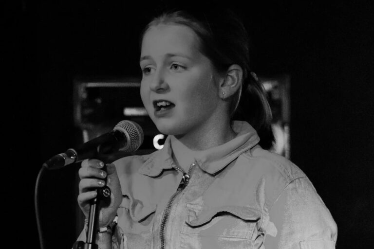 teenager in a denim jacket singing into a microphone to make money