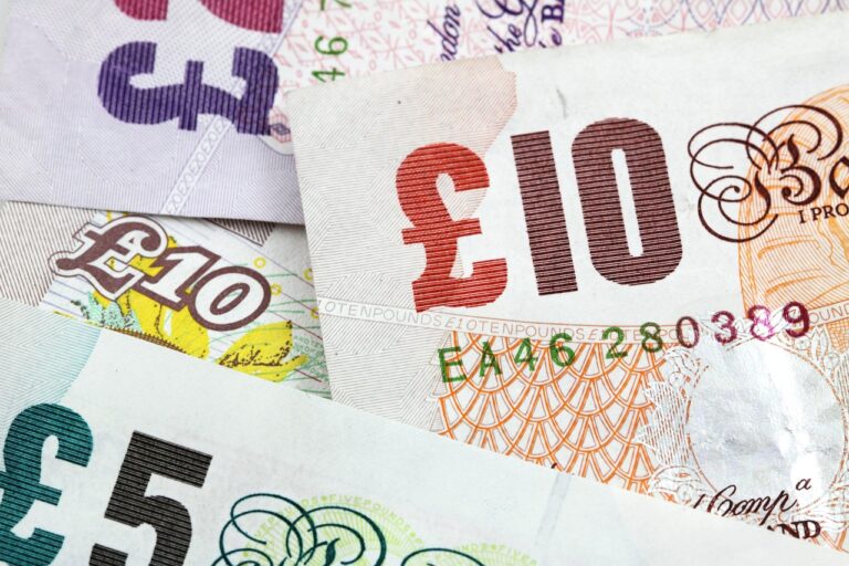 several British bank notes in £5 and £10 denominations laid down together to indicate money saving
