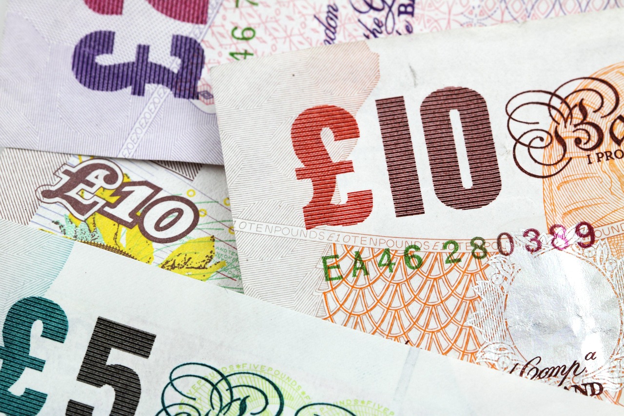 several British bank notes in £5 and £10 denominations laid down together to indicate money saving