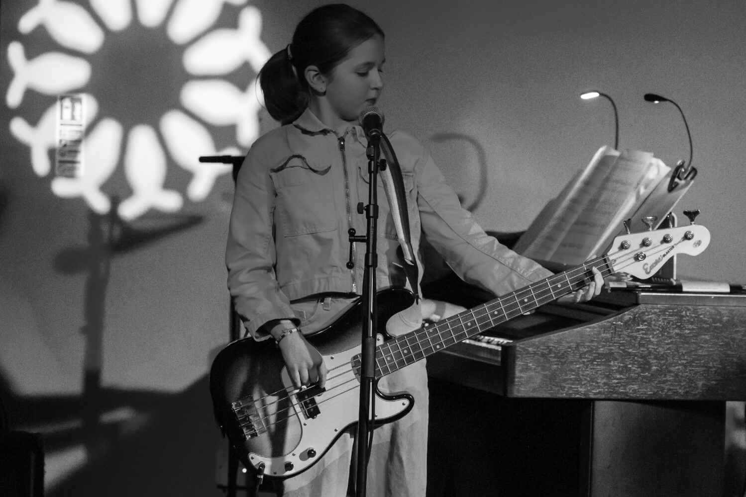 Teenager performing on stage playing a bass guitar and singing